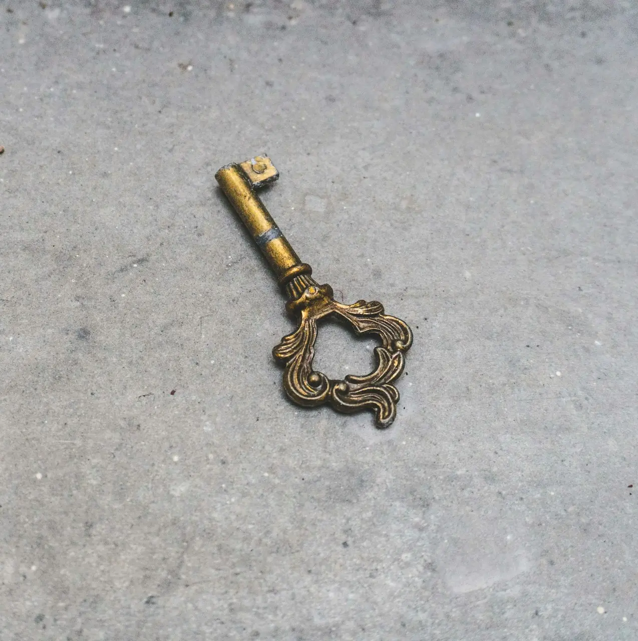 gold skeleton key on gray concrete floor